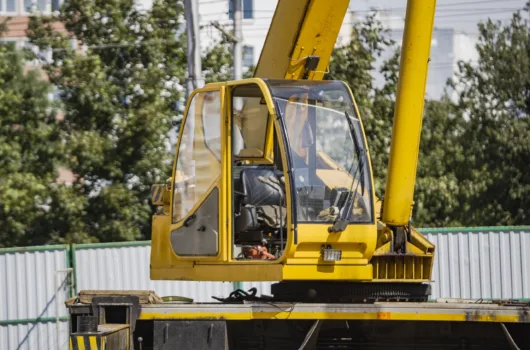 Guindaste móvel compacto operando em área urbana com cabine de controle visível para operações em espaços reduzidos